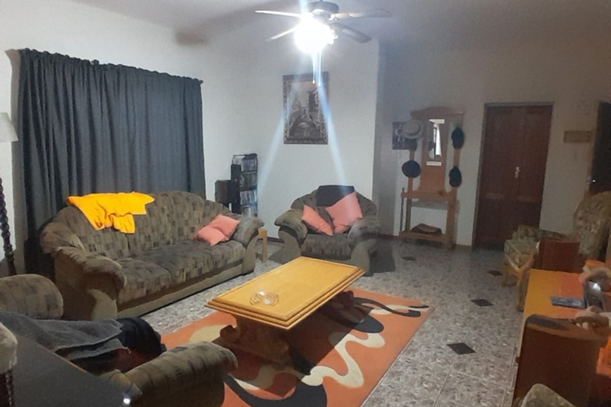 A spacious living room featuring tiled flooring and a central ceiling fan, providing a functional and comfortable area for relaxation.