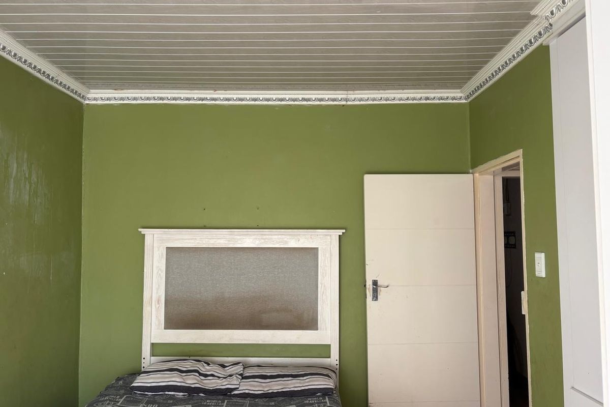 A bedroom featuring green walls, a white built-in wardrobe, and decorative ceiling cornicing with PVC paneling.