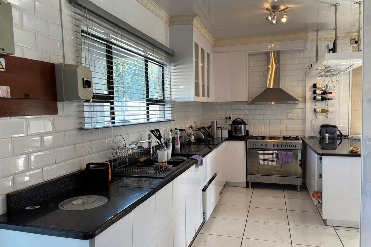 A functional kitchen featuring white subway tile backsplash, granite countertops, stainless steel gas stove, and extractor fan with ample built-in cabinetry.