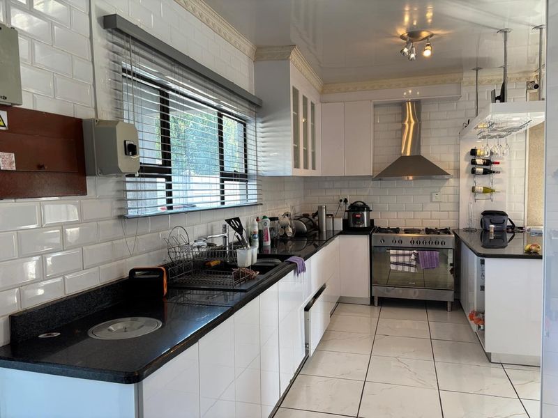 A functional kitchen featuring white subway tile backsplash, granite countertops, stainless steel gas stove, and extractor fan with ample built-in cabinetry.