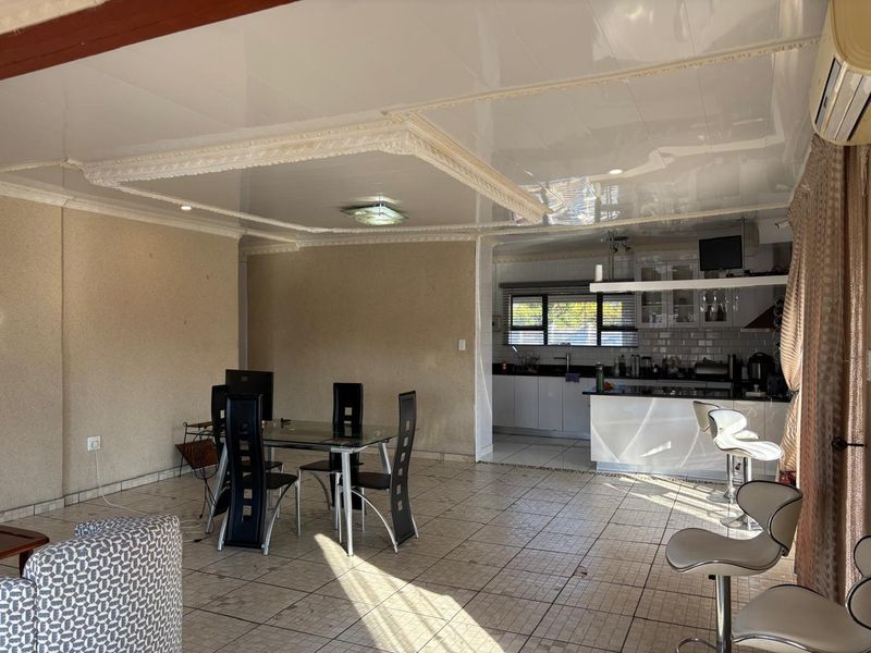 Open-plan living and kitchen area featuring a glossy coffered ceiling, tiled flooring, and a functional kitchen island with breakfast bar seating.