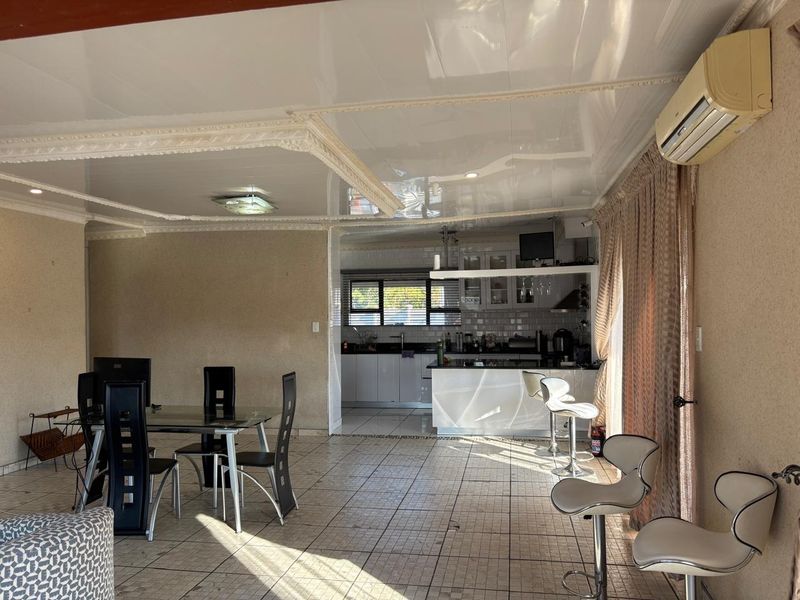 Open-plan living and kitchen area featuring tiled flooring, a central kitchen island, and a split-system air conditioner.