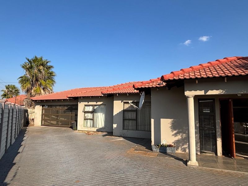 Front exterior view of a single-story house featuring a paved driveway, tiled roof, and a covered entrance with a concrete column.