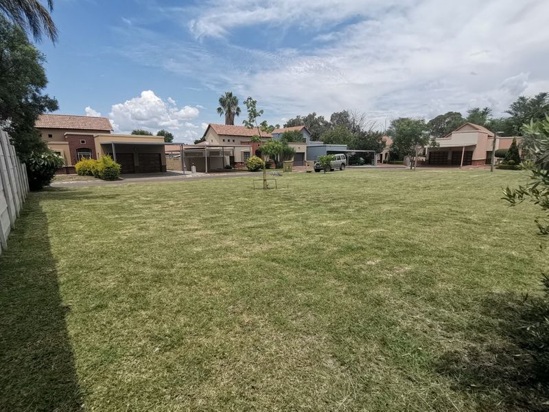A well-maintained, expansive residential lawn area bordered by perimeter fencing, situated within a suburban estate setting.