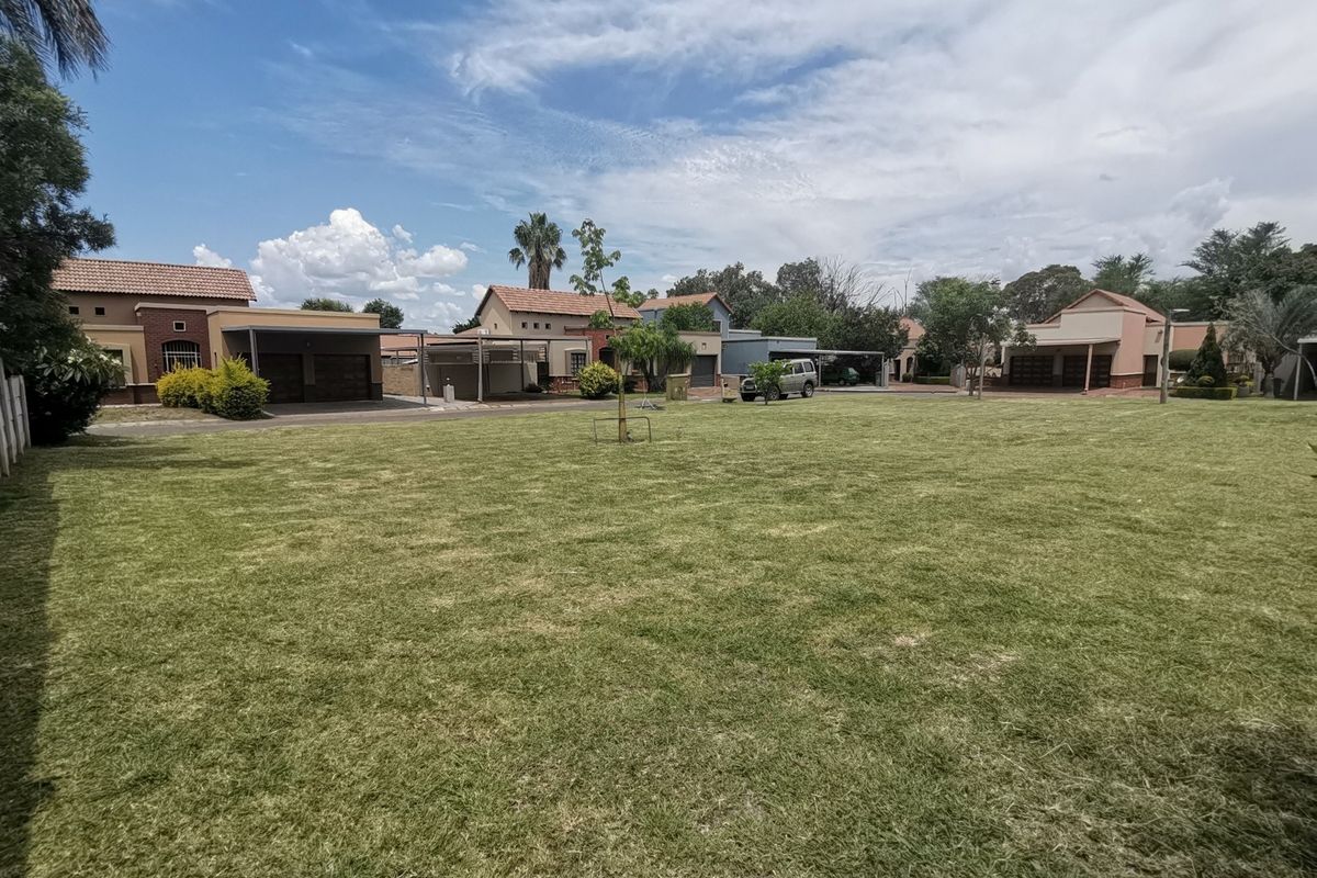 A spacious, well-maintained residential lawn area situated within a suburban estate, offering a clear view of surrounding neighboring properties.