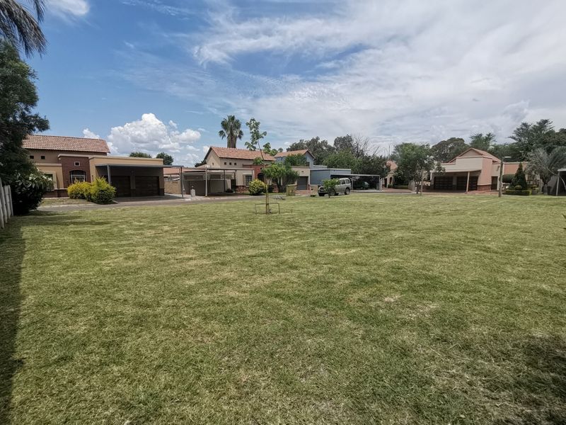 A spacious, well-maintained residential lawn area situated within a suburban estate, offering a clear view of surrounding neighboring properties.