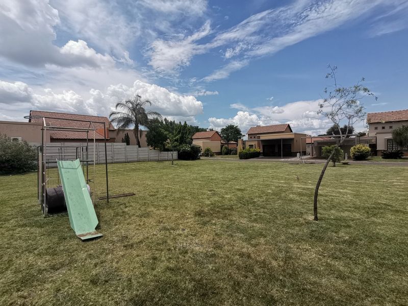 A spacious residential garden area featuring a well-maintained lawn and secure precast concrete boundary walling in a suburban setting.