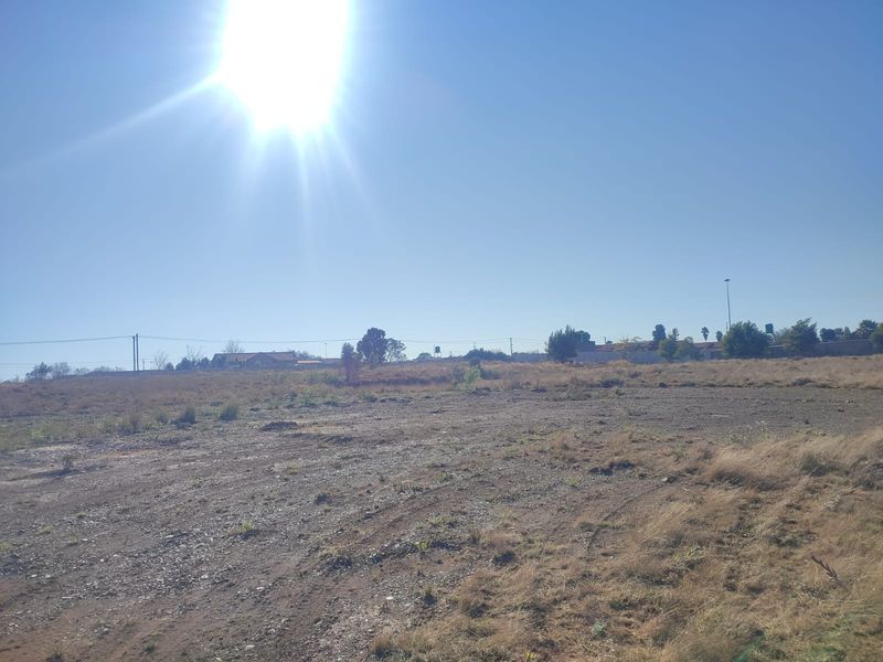 A view of a vacant residential plot of land with dry grass and open space.