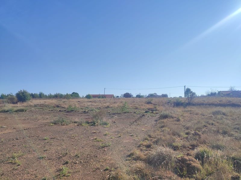 A view of a vacant residential plot featuring natural terrain and overhead power lines, suitable for future development.