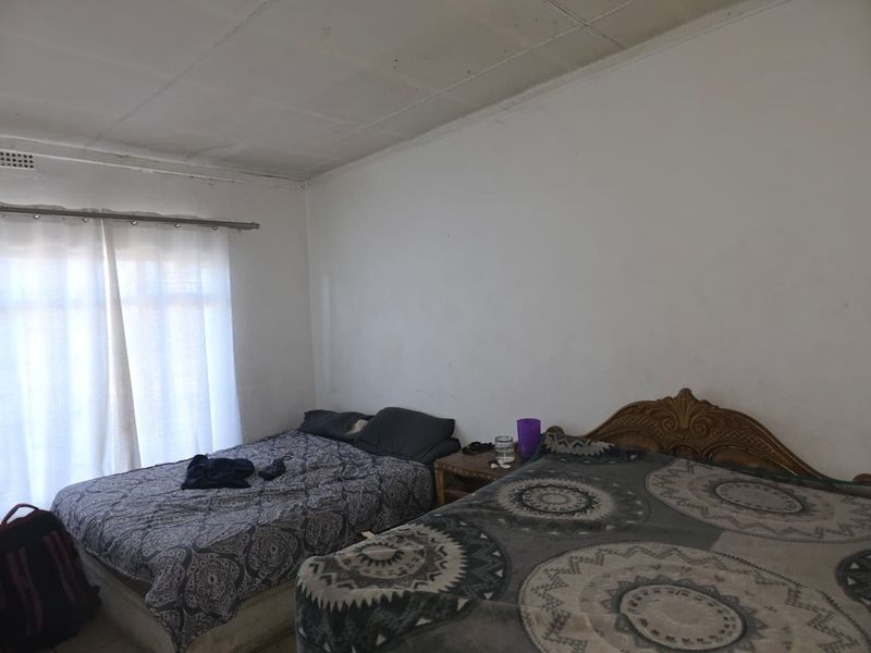 A bedroom featuring a simple layout with a window and ceiling tiles showing signs of wear and aging.