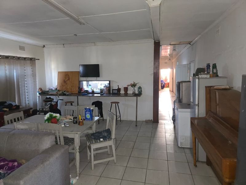 Open plan living and dining area featuring tiled flooring and a breakfast bar with a pass-through window connecting to the kitchen.
