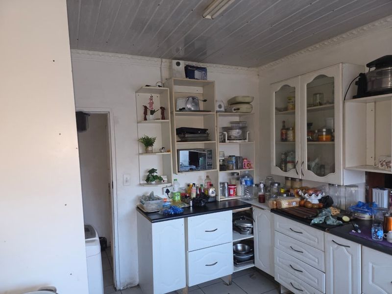 A functional kitchen featuring white cabinetry, open shelving, and laminate countertops, offering a practical layout with potential for cosmetic updates.