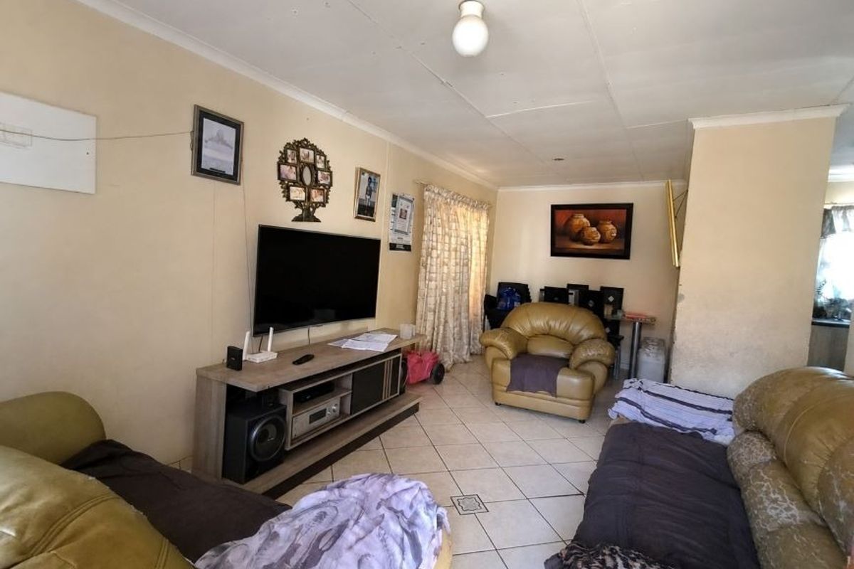 A living room featuring tiled flooring and coved ceilings, offering a functional space that would benefit from cosmetic updates to the walls and finishes.