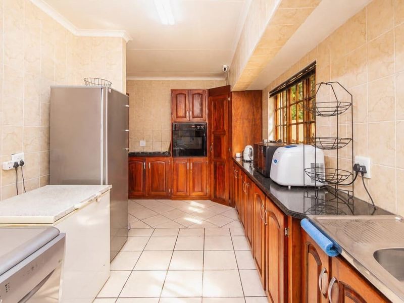 A functional kitchen featuring traditional wooden cabinetry, granite countertops, tiled walls, and built-in oven, offering a classic layout with ample storage space.
