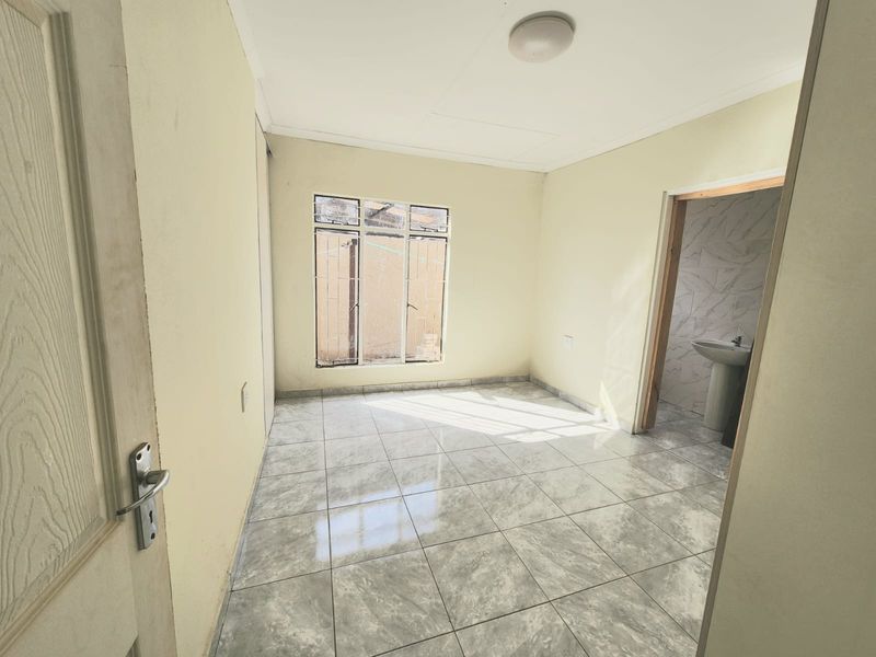 A vacant bedroom featuring tiled flooring, a built-in cupboard, and direct access to an en-suite bathroom.