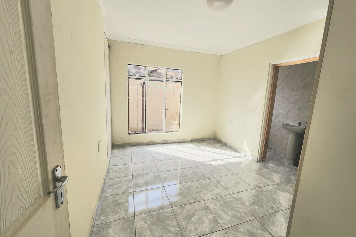 A vacant bedroom featuring tiled flooring, a built-in cupboard, and direct access to an en-suite bathroom.