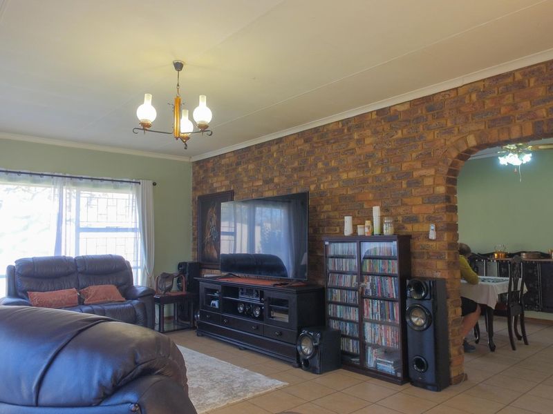 Spacious living room featuring an exposed brick feature wall, a distinctive brick archway leading to the dining area, and neutral tiled flooring.