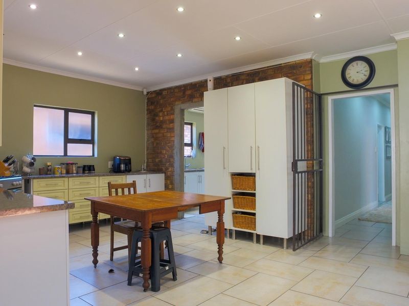A functional kitchen featuring built-in cabinetry, laminate countertops, and an exposed brick wall, with tiled flooring and recessed lighting throughout.