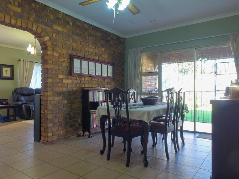Open plan living and dining area featuring exposed brick archway, tiled flooring, and sliding glass doors leading to the exterior.