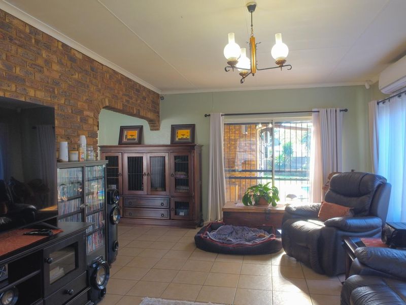 Spacious living room featuring an exposed brick feature wall, brick archway, ceramic tiled flooring, and a split-system air conditioner with access to the patio.