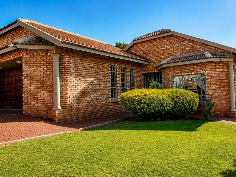 A well-maintained face brick house featuring a tiled roof, paved driveway, integrated garage, and established front garden.