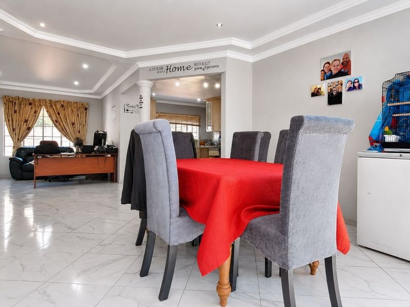 Spacious open-plan living and dining area featuring tiled flooring, recessed downlighting, and a coved ceiling, creating a bright and versatile living space.