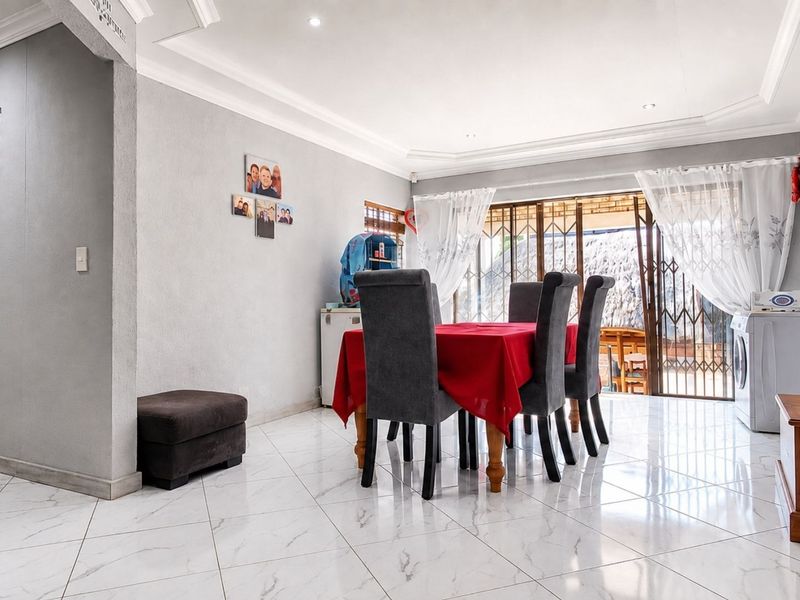 A bright dining area featuring modern marble-look floor tiles, recessed ceiling lighting, and a sliding glass door providing access to the outdoor space.