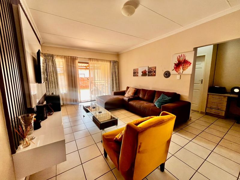 A well-lit living room featuring tiled flooring, coved ceilings, and a sliding glass door providing access to the outdoor area.