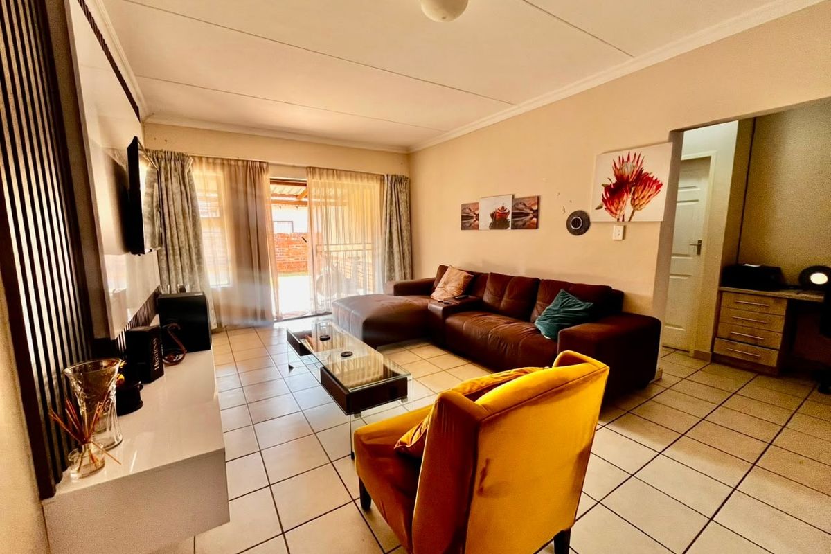 A well-lit living room featuring tiled flooring, coved ceilings, and a sliding glass door providing access to the outdoor area.