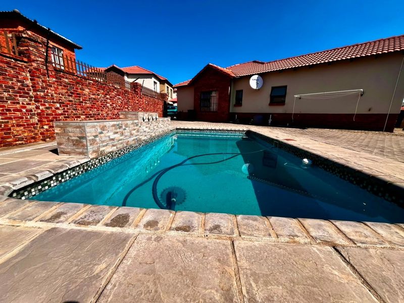 Outdoor pool area featuring a tiled swimming pool, paved surround, and brick boundary wall, set within a private townhouse courtyard.