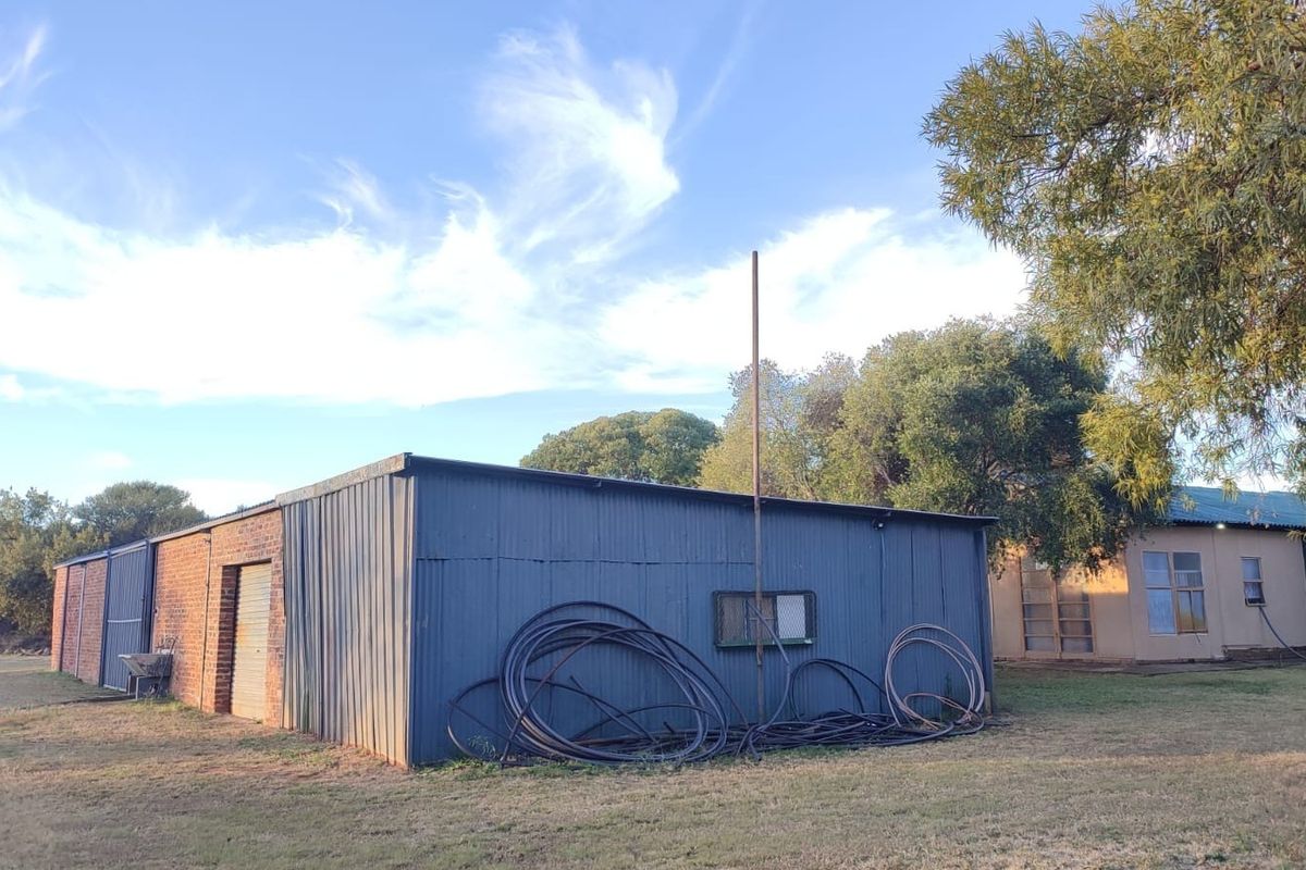 Exterior view of a farm outbuilding featuring corrugated metal cladding and brick masonry construction set within a rural landscape.