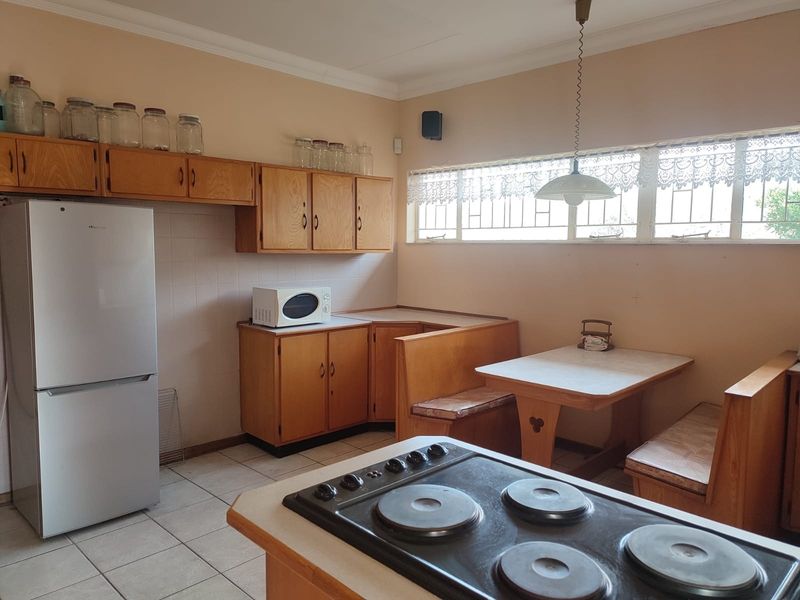 A functional kitchen featuring built-in wooden cabinetry, a tiled splashback, a built-in breakfast nook, and an integrated electric hob.