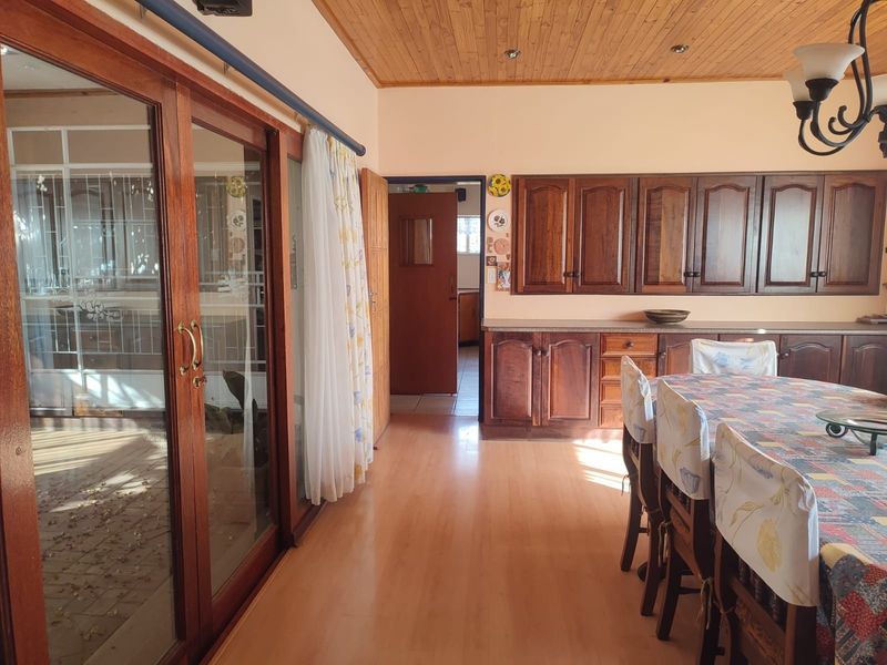 Dining area featuring timber ceiling, laminate flooring, and built-in wooden cabinetry, with direct access to an outdoor patio through sliding glass doors.