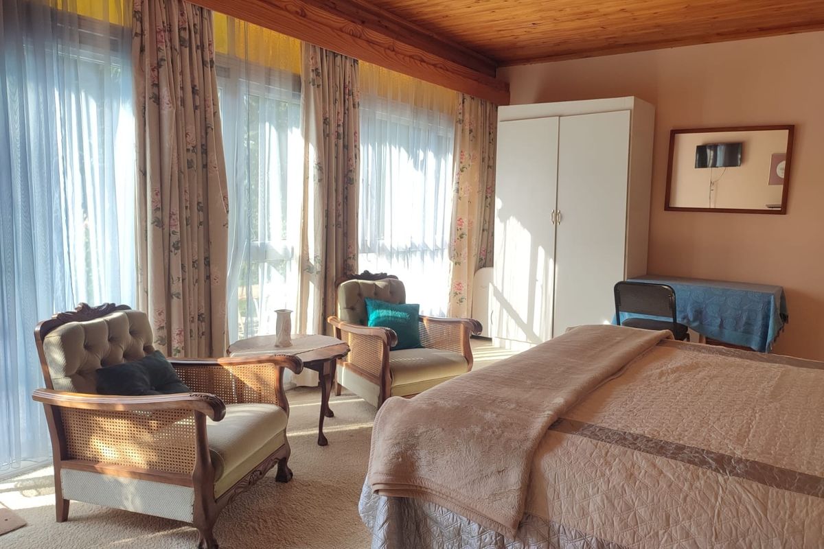 Spacious bedroom featuring a warm timber ceiling, large sliding glass doors for natural light, and a built-in wardrobe.