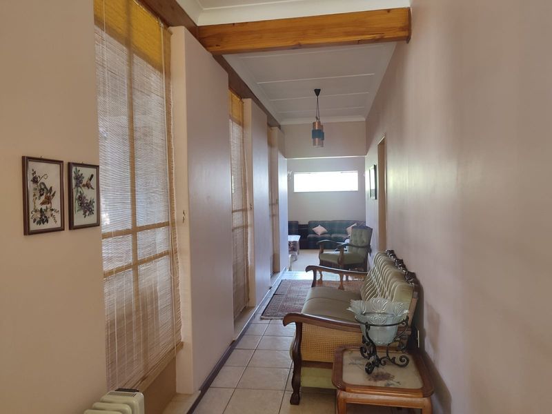 A long hallway featuring tiled flooring and an exposed timber ceiling beam, providing access to adjacent living areas.