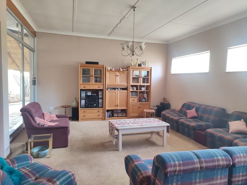 A spacious living room featuring carpeted flooring, a ceiling-mounted light fixture, and large sliding glass doors providing access to the outdoor area.