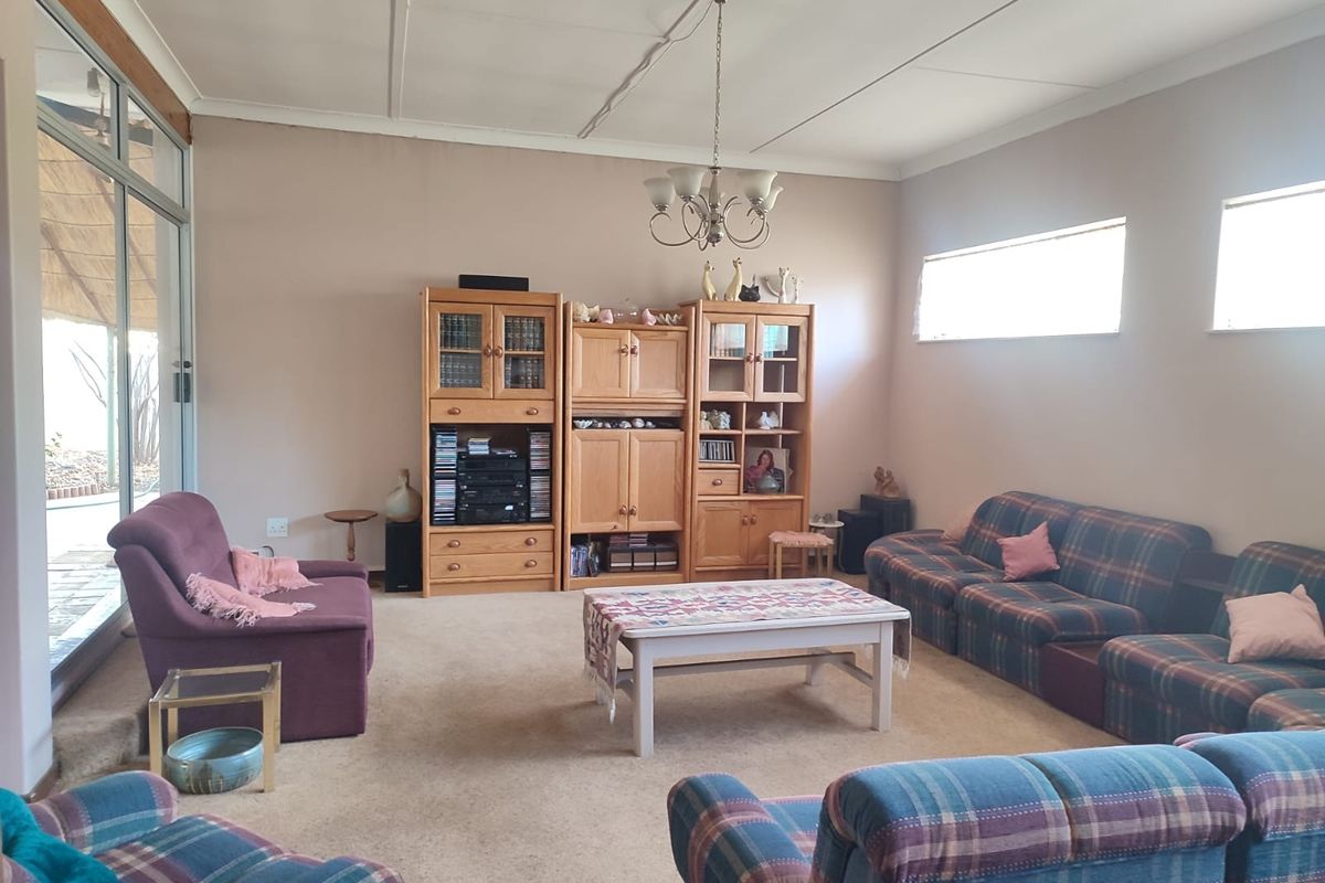 A spacious living room featuring carpeted flooring, a ceiling-mounted light fixture, and large sliding glass doors providing access to the outdoor area.