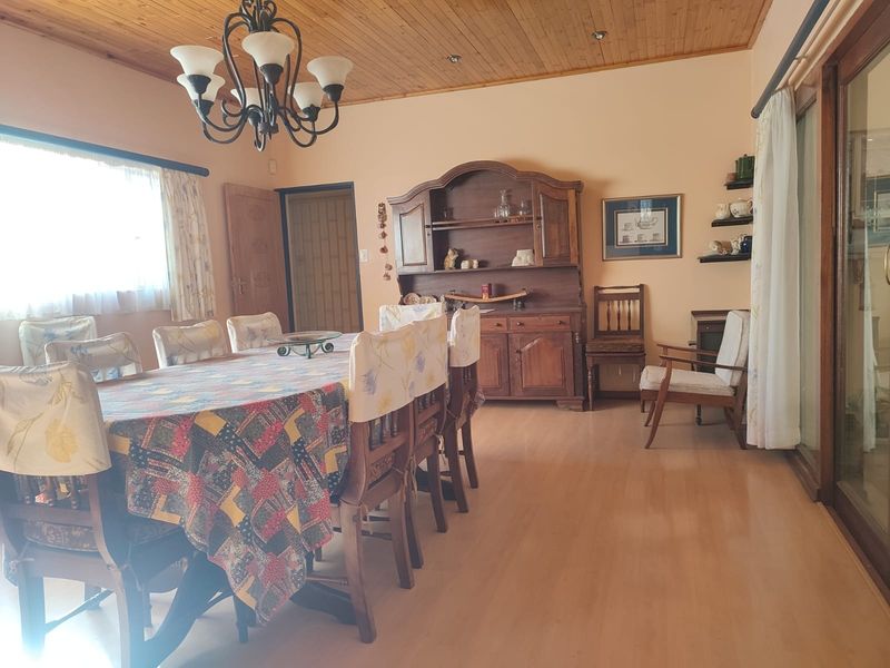 Spacious dining room featuring a timber-paneled ceiling, laminate flooring, and sliding glass doors that provide natural light and access to the outdoors.