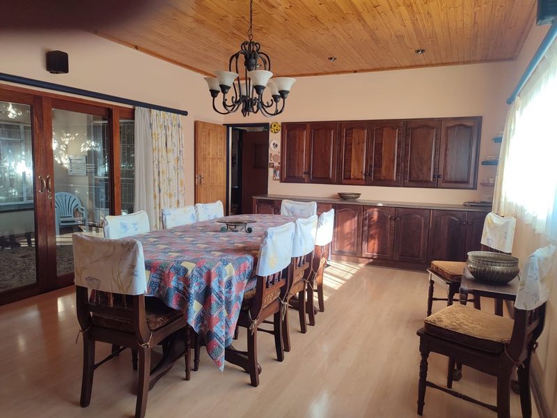 Spacious dining room featuring a timber ceiling, laminate flooring, and extensive built-in wooden cabinetry, with direct access to an outdoor patio area.