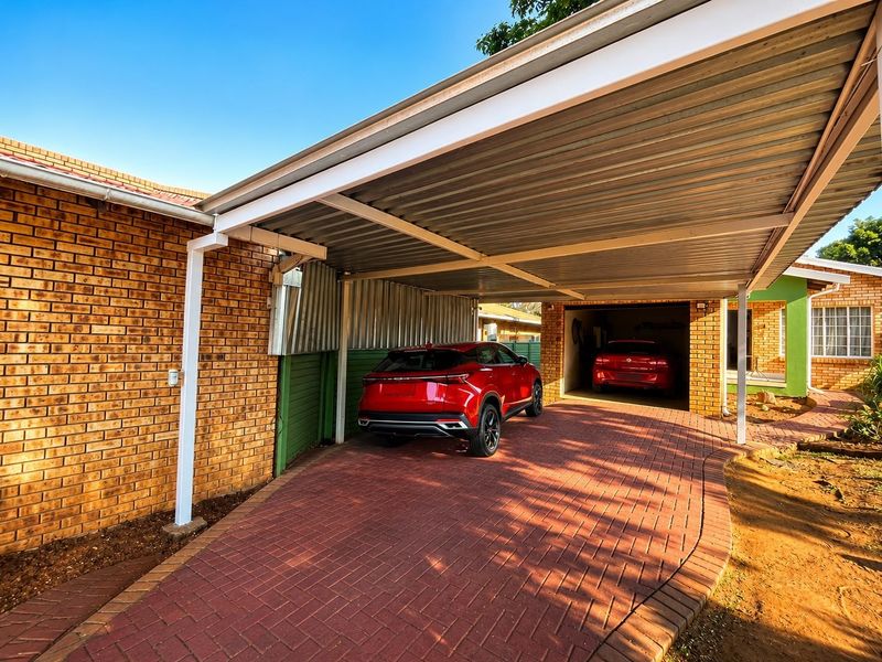 A functional property exterior featuring a covered carport area and an enclosed garage, complemented by neat brick paving.
