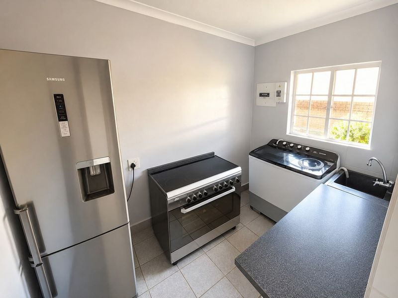 A functional laundry area featuring tiled flooring, a built-in sink with faucet, and an electrical distribution board.
