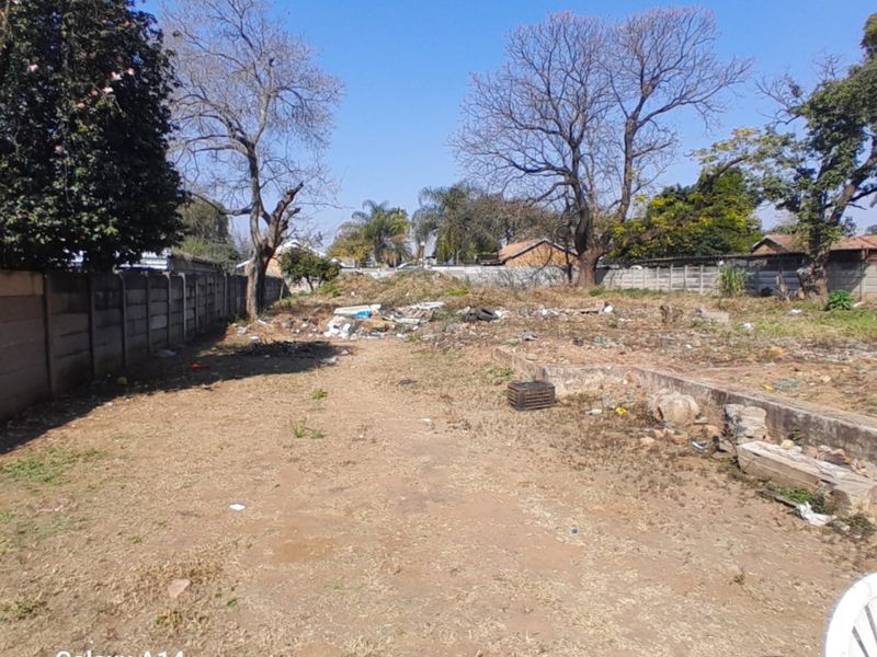 A vacant residential plot featuring a precast concrete boundary wall and retaining wall, currently requiring significant clearing of debris and site maintenance.