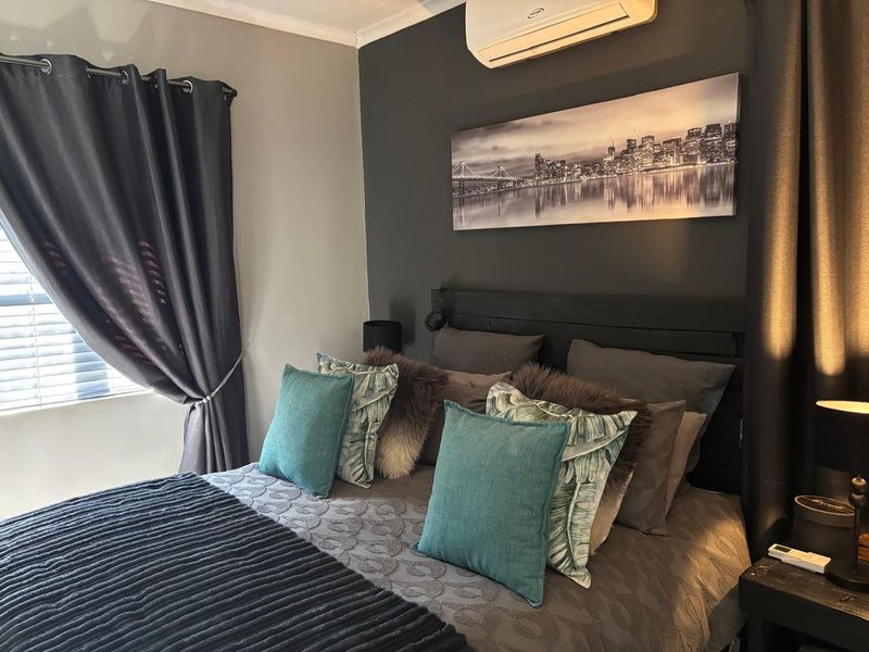 A well-maintained bedroom featuring a dark accent wall, split-system air conditioning, and window blinds, creating a cozy and functional sleeping space.