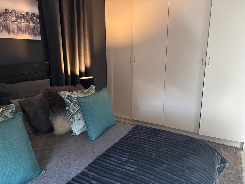 A cozy bedroom featuring neutral walls and practical built-in cupboards, providing ample storage space within a comfortable living environment.