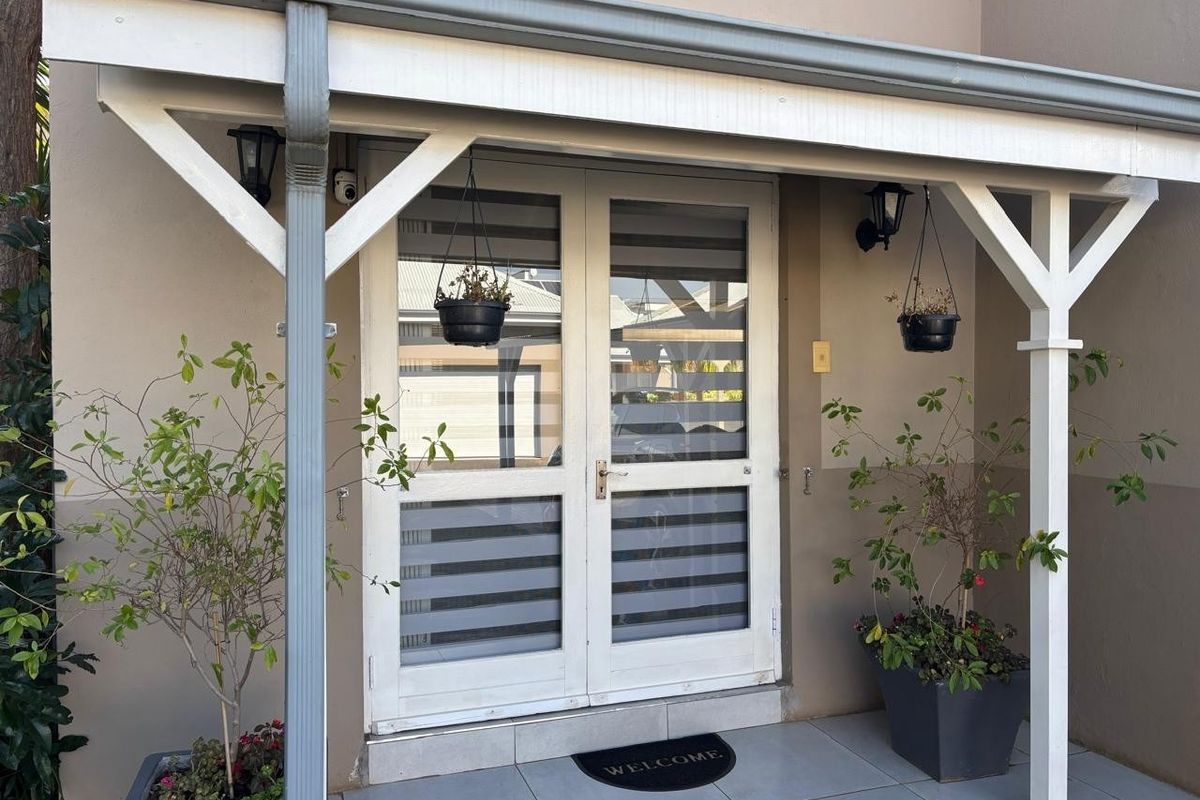 A welcoming entrance featuring a covered porch with tiled flooring and double glass doors with fitted blinds.
