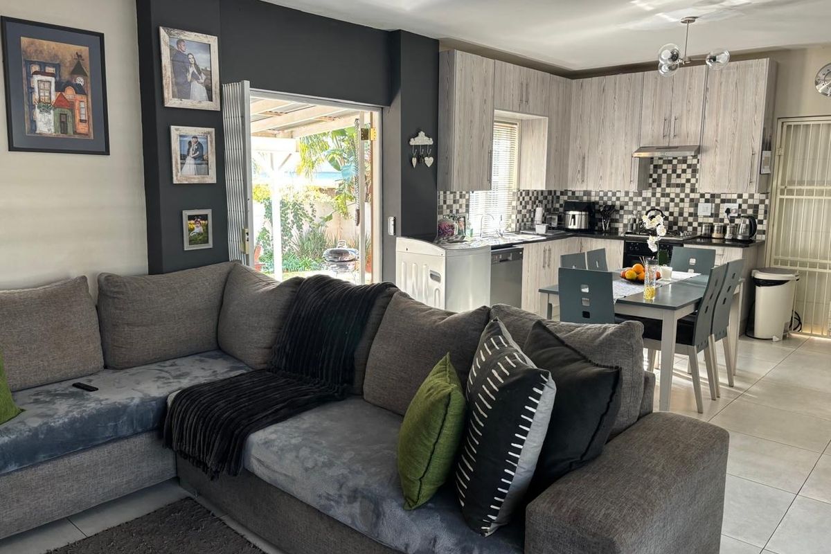 Open-plan living and dining area featuring a modern kitchen with built-in cabinetry, tiled floors, and direct access to the outdoor patio.