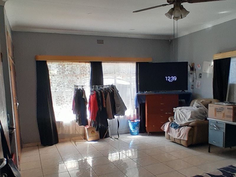 A living room featuring tiled flooring and a ceiling fan, offering a functional space with neutral wall finishes.