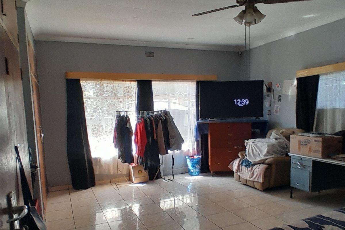 A living room featuring tiled flooring and a ceiling fan, offering a functional space with neutral wall finishes.