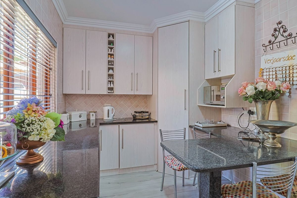 A functional kitchen featuring light-toned built-in cabinetry, dark granite countertops, a tiled backsplash, and a built-in microwave unit.