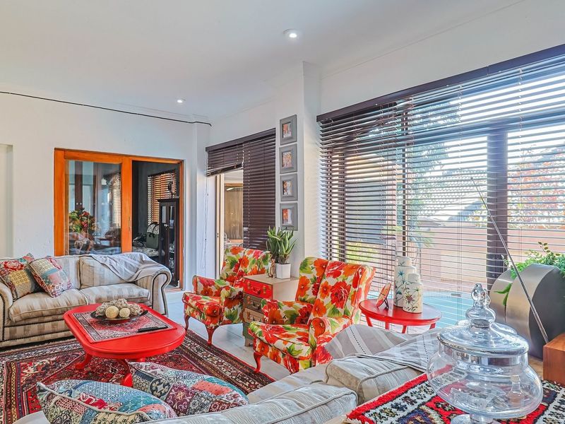 A bright and spacious living room featuring large sliding glass doors, venetian blinds, and recessed downlighting, creating a comfortable and well-lit living environment.